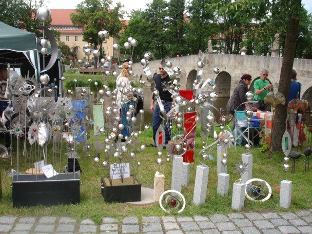 Eine Gruppe von Menschen steht um eine Ausstellung von Metallskulpturen herum