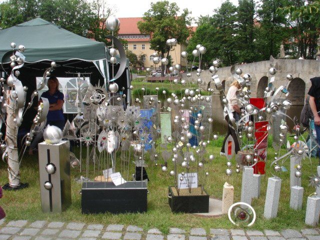 Eine Ausstellung von Skulpturen in einem Park mit einem grünen Zelt im Hintergrund
