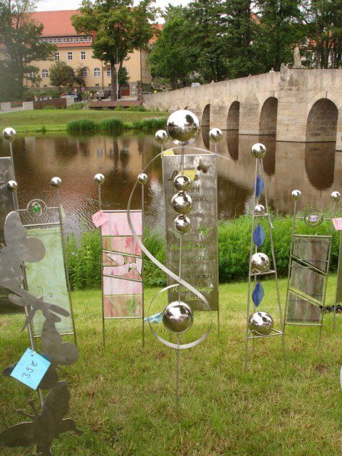Eine Reihe von Skulpturen im Gras mit einer Brücke im Hintergrund