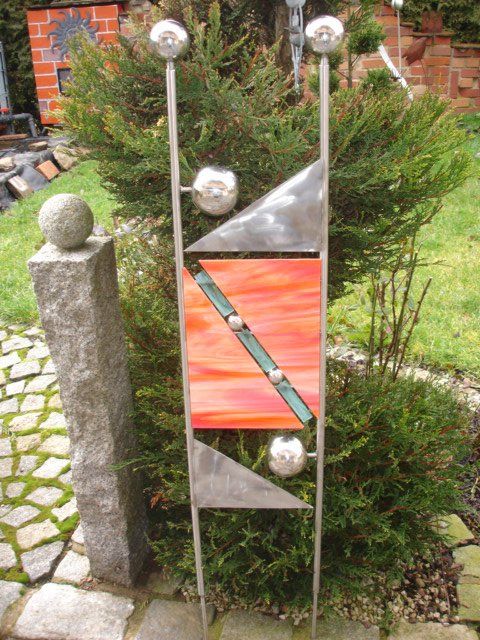 Eine Skulptur sitzt vor einem Busch in einem Garten