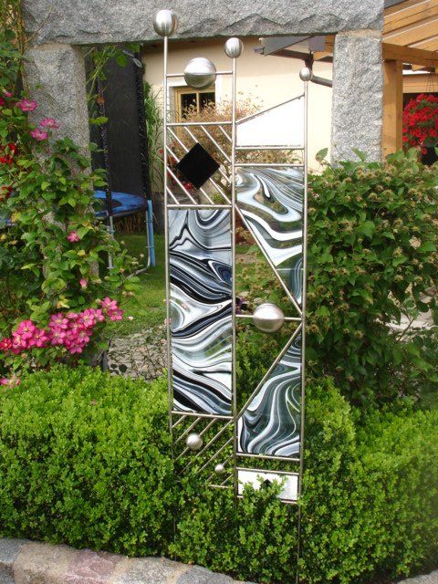 Eine Edelstahlskulptur steht mitten in einem Garten