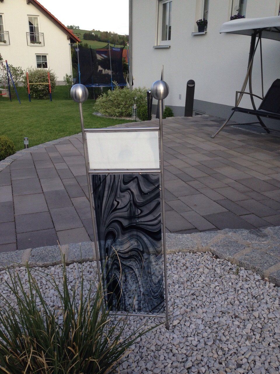 Ein Schild aus Edelstahl steht vor einem Haus