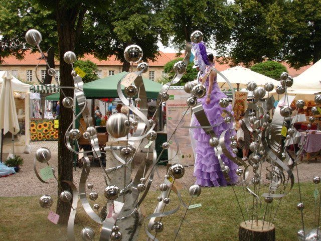 Eine Frau in einem lila Kleid steht vor einer Skulptur