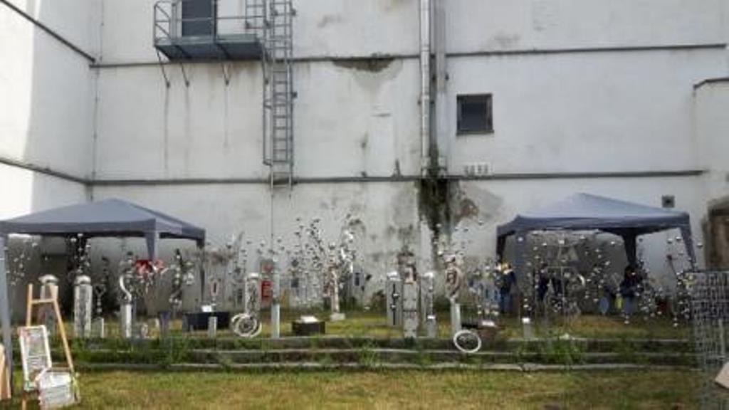 Ein weißes Gebäude mit einer Feuertreppe und ein paar Zelten davor.