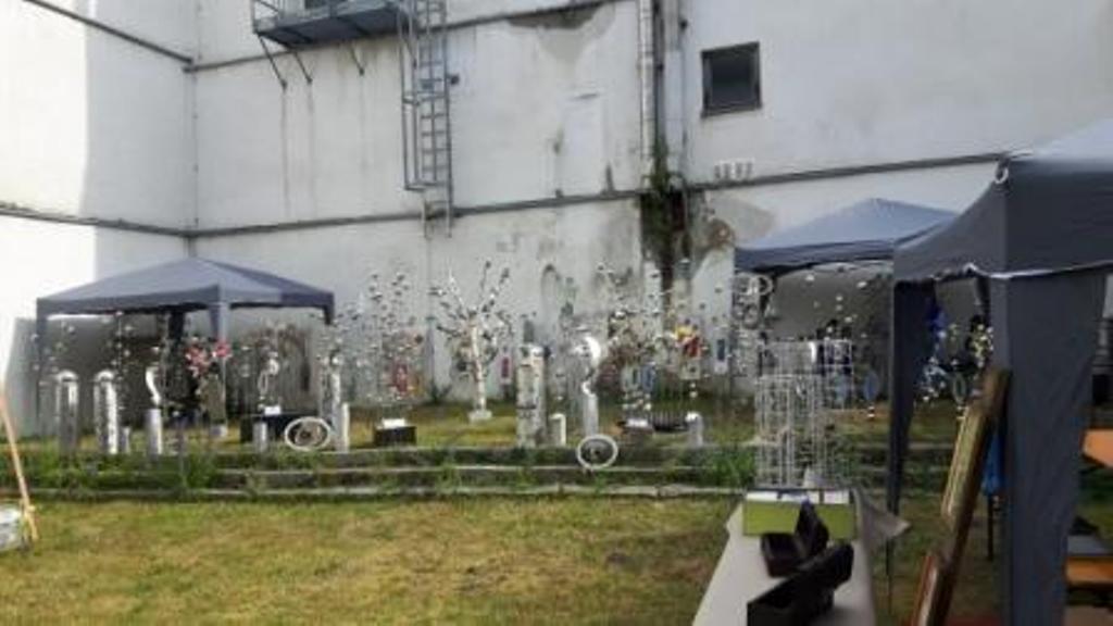 Eine Gruppe von Zelten steht auf einer Rasenfläche vor einem Gebäude.