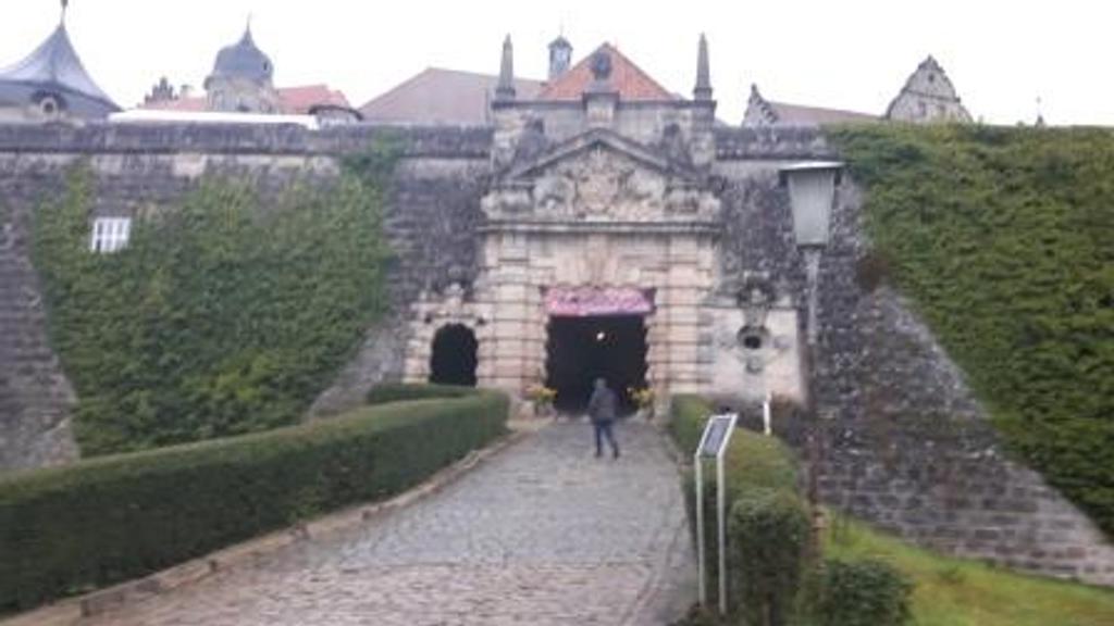 Ein Mann geht einen Kopfsteinpflasterweg entlang auf ein Schloss zu.