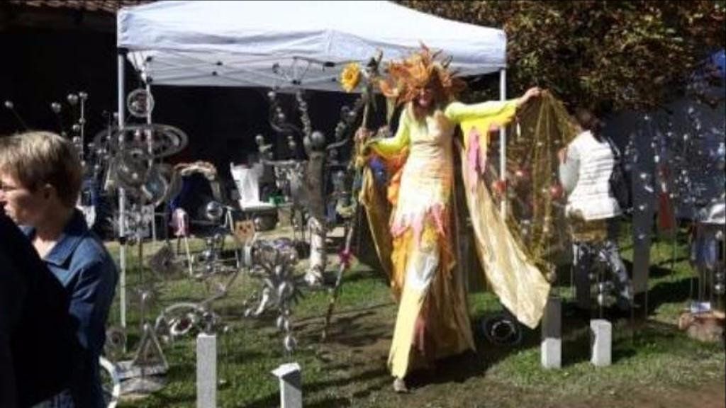 Eine Frau läuft auf Stelzen vor einem Zelt.