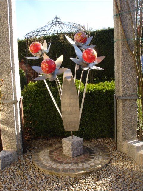 Eine Skulptur aus Blumen mit roten Kugeln darauf