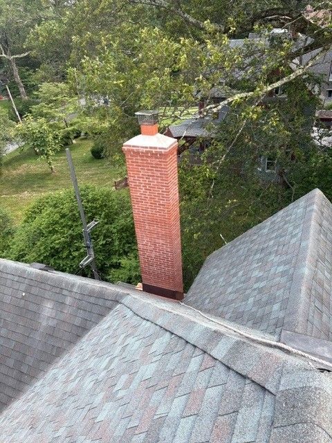 A brick chimney is on the roof of a house.
