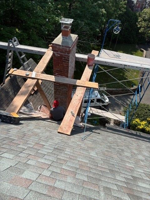 A brick chimney is being built on top of a roof.