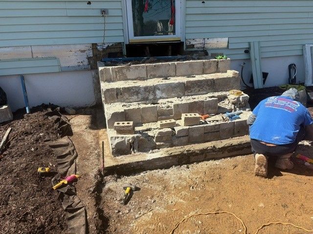 A man in a blue shirt is working on a set of stairs