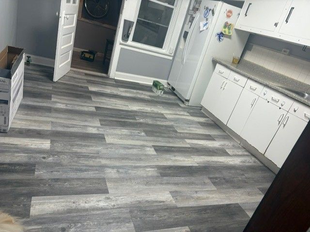 A kitchen with a wooden floor and white cabinets