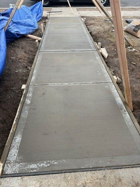 A concrete sidewalk is being built on the side of the road