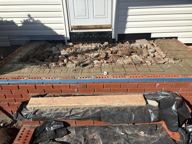 A brick walkway is being built in front of a house.