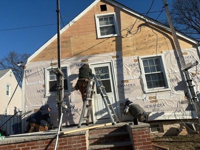 A group of people are working on the side of a house.