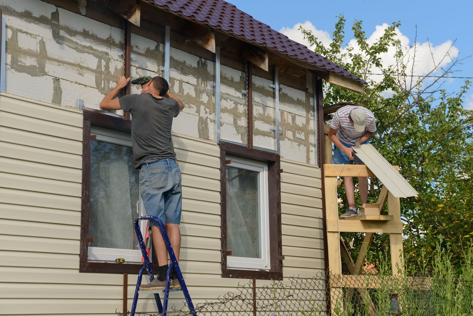 Two men are working on the side of a house.
