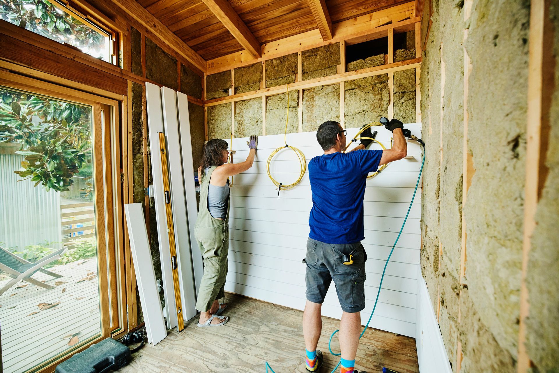 A man and a woman are working on a wall in a room.