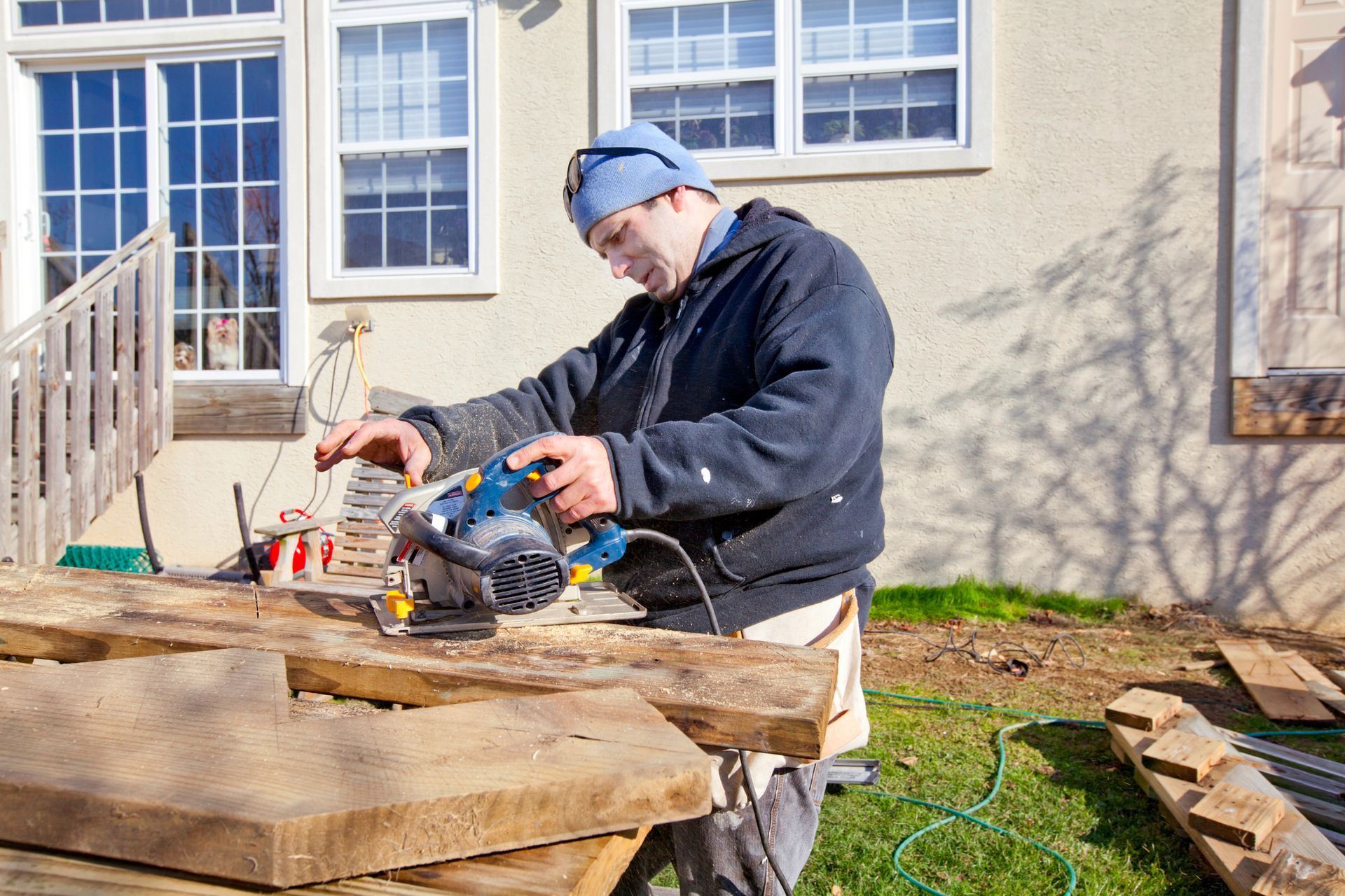 A man is using a circular saw to cut a piece of wood.
