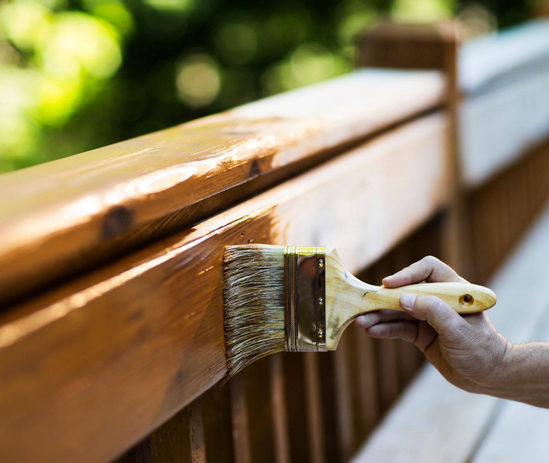 A person is painting a wooden railing with a brush.