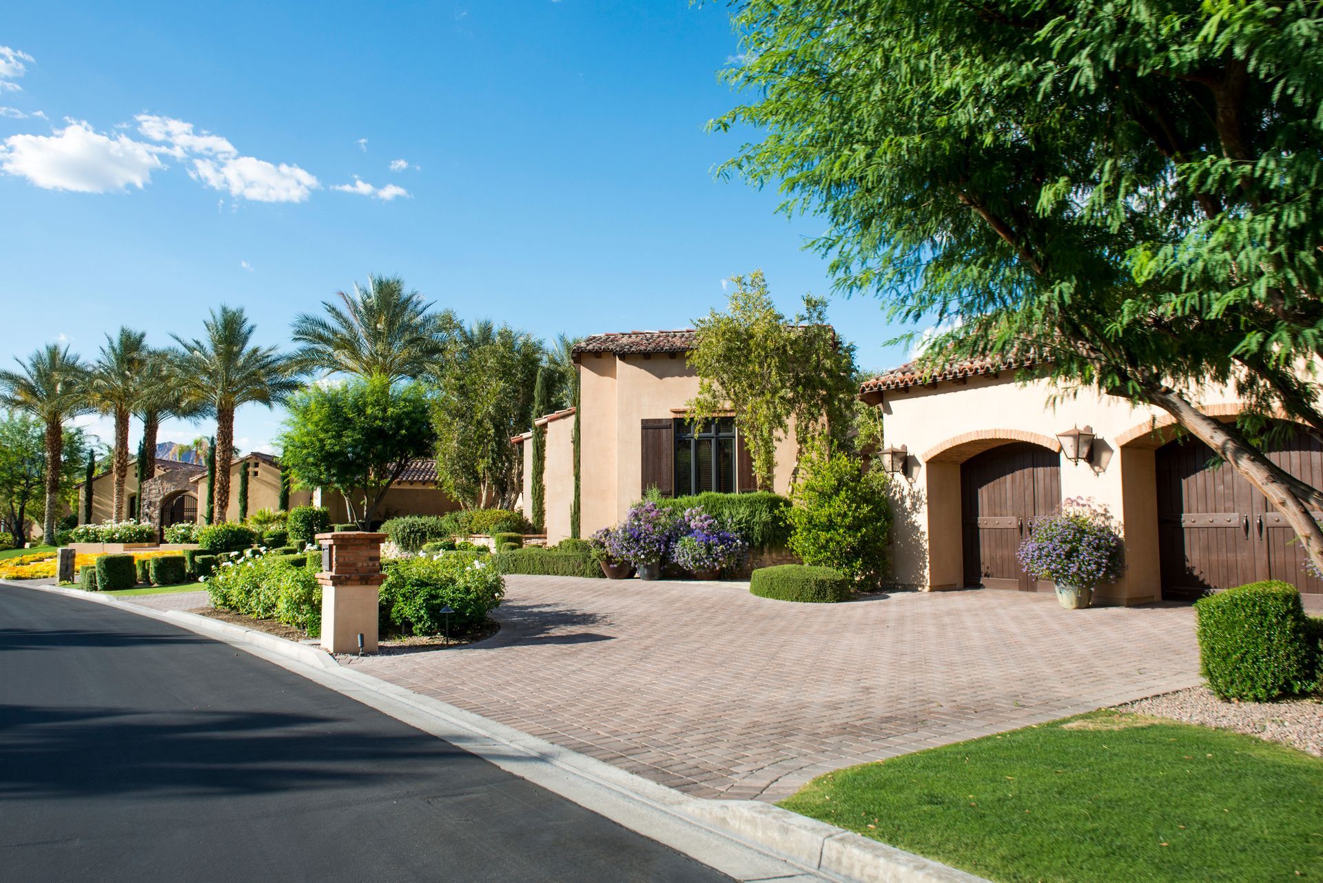 A row of houses on a sunny day with palm trees on the side of the road.