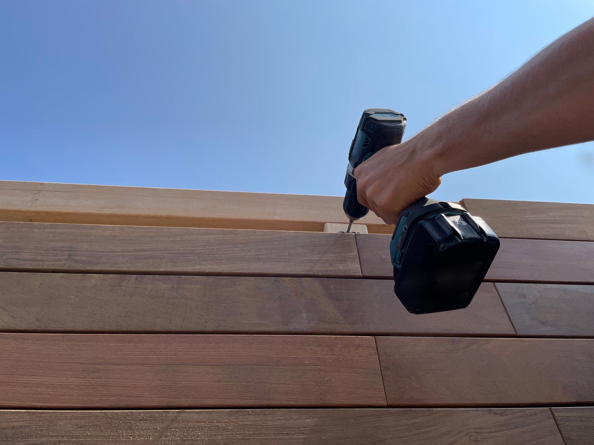 A person is using a drill on a wooden surface