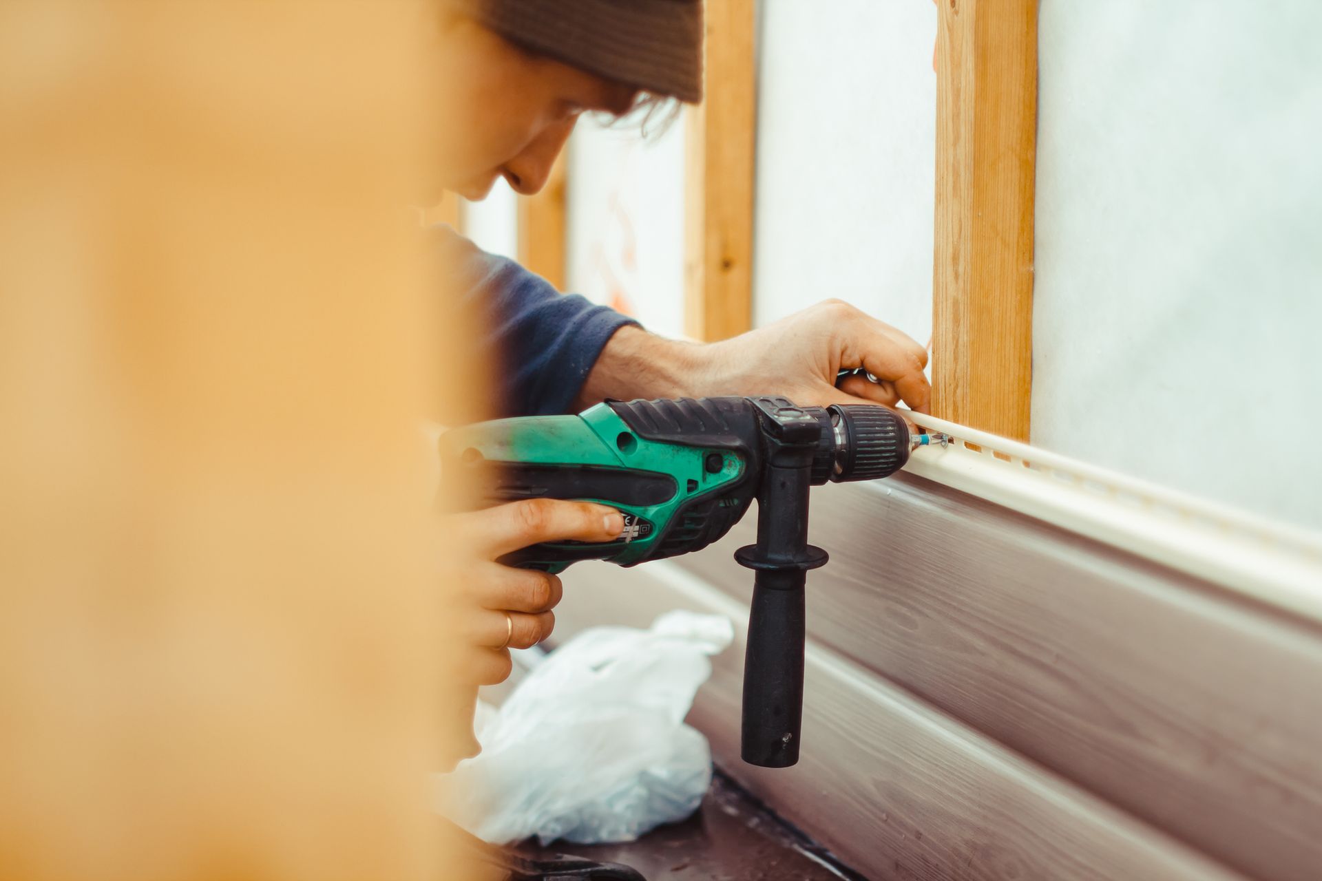 A man is using a hammer drill to drill a hole in a wall.
