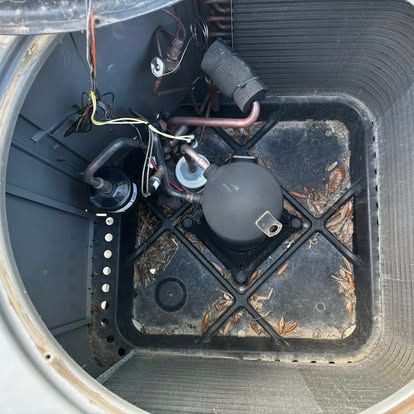 Open air conditioning unit interior, showing a compressor, tubing, and wiring.