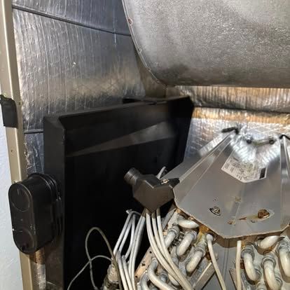 HVAC unit interior with metal components, insulation, and wiring, in a room.