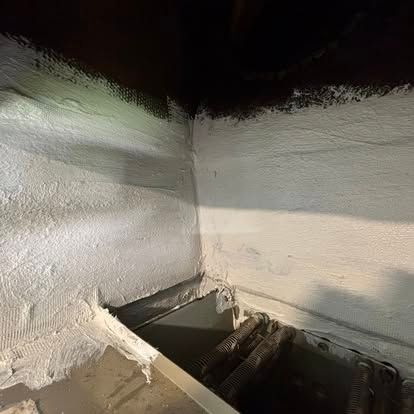 White-painted basement corner with dark ceiling. Metal staircase visible leading down.