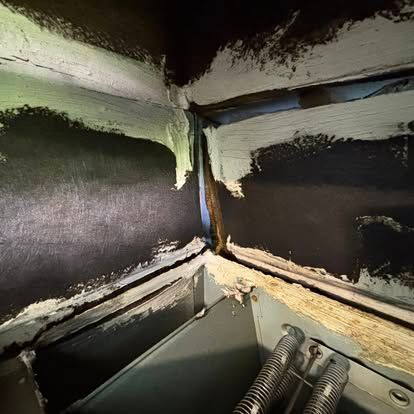 Dark, enclosed corner with gray sealant along edges. A metal element is visible at the bottom.