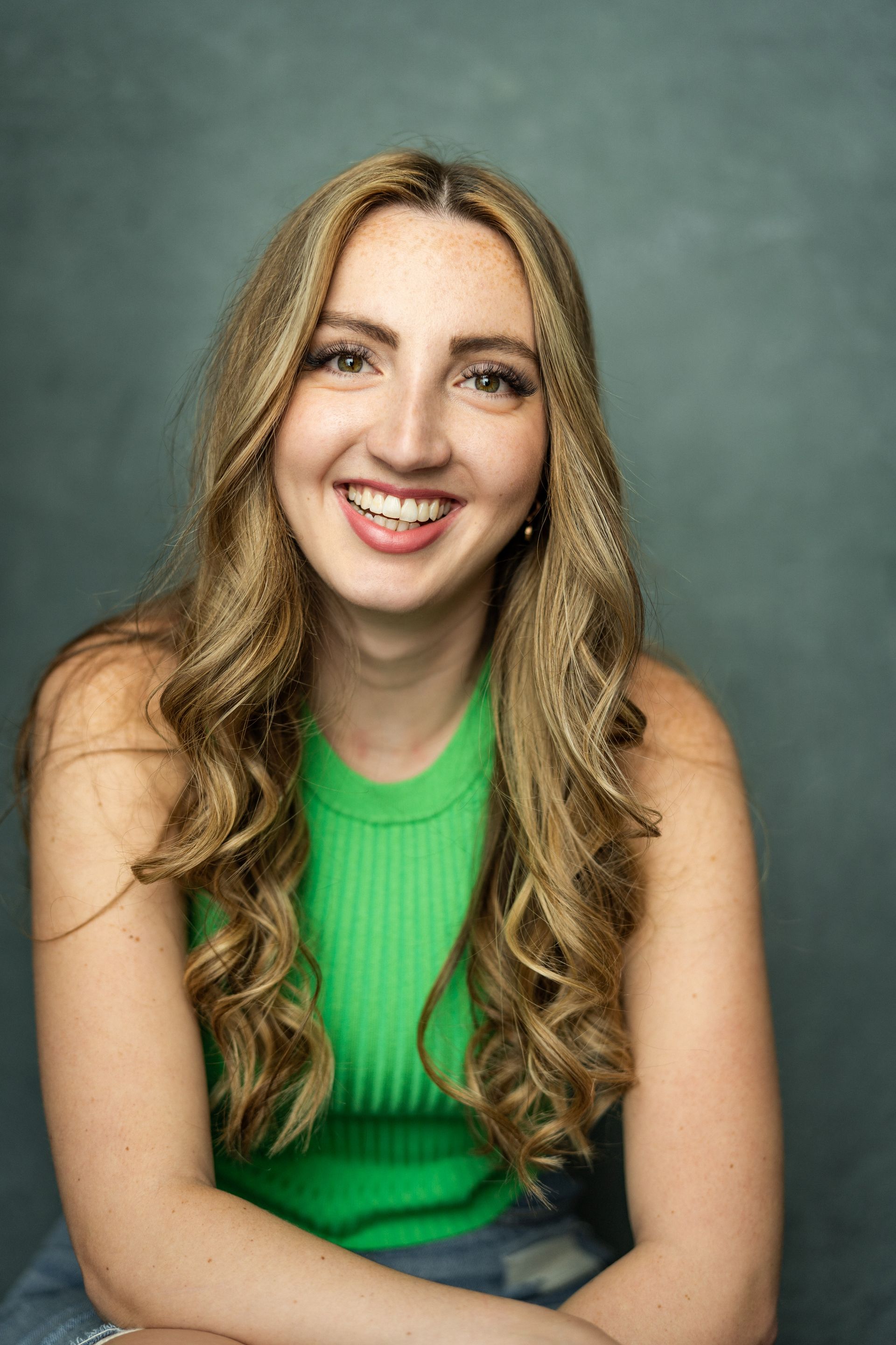 The woman is wearing a green tank top and smiling for the camera.