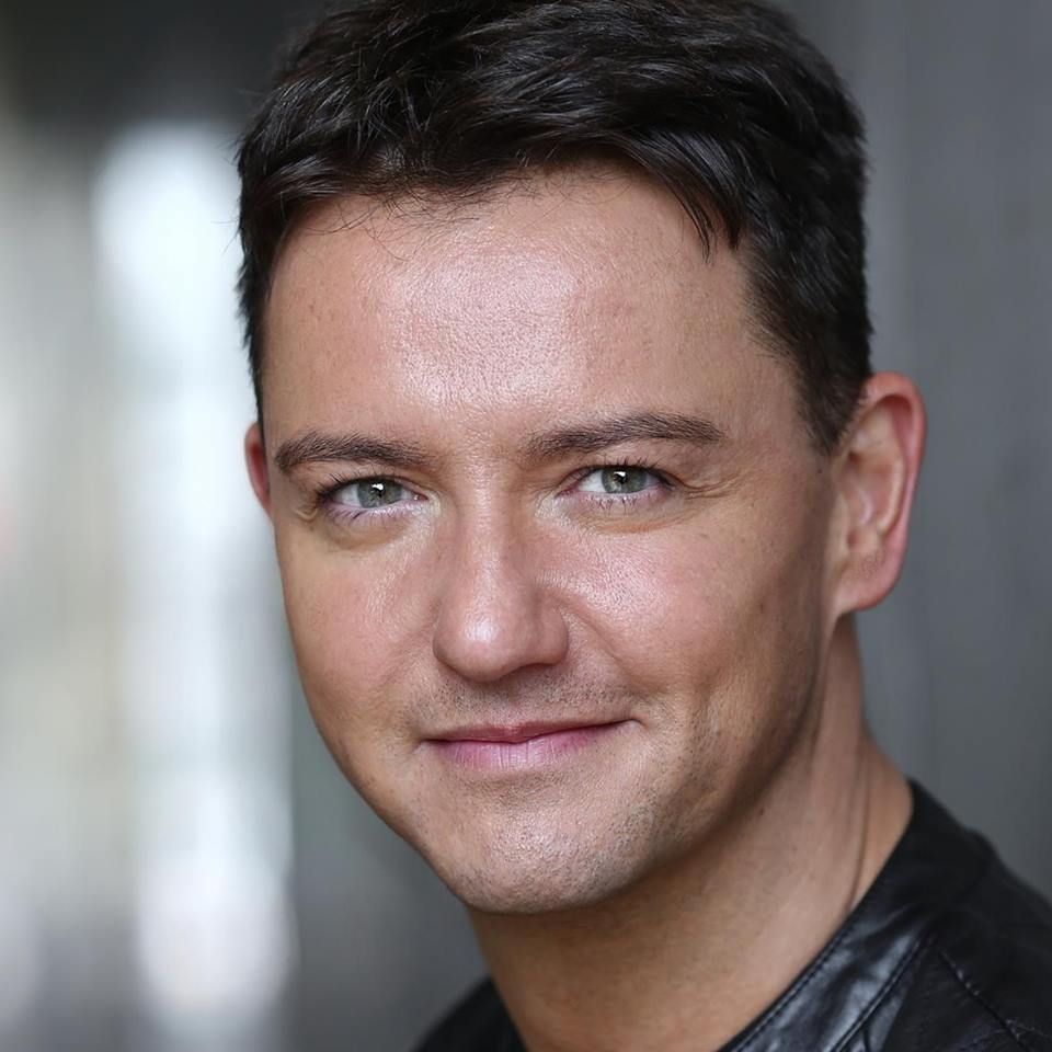A man in a black jacket is smiling for the camera.