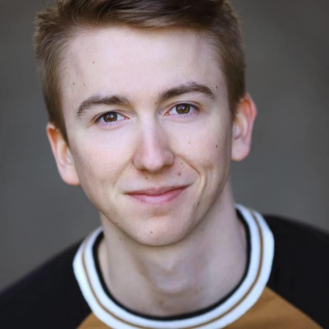 A young man wearing a brown and black shirt is smiling for the camera.