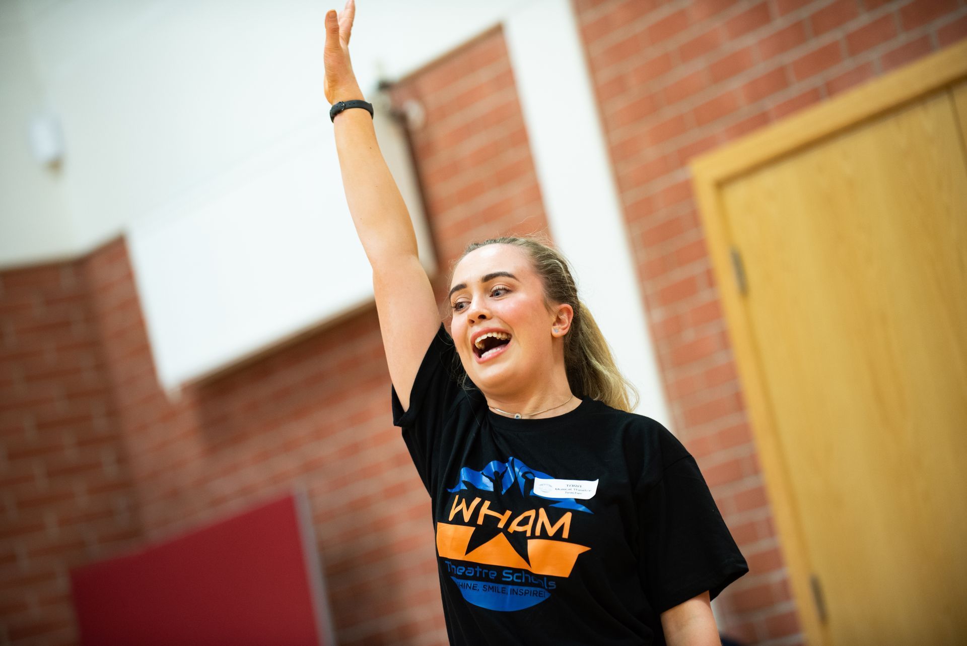 A woman in a black shirt is raising her hand in the air.