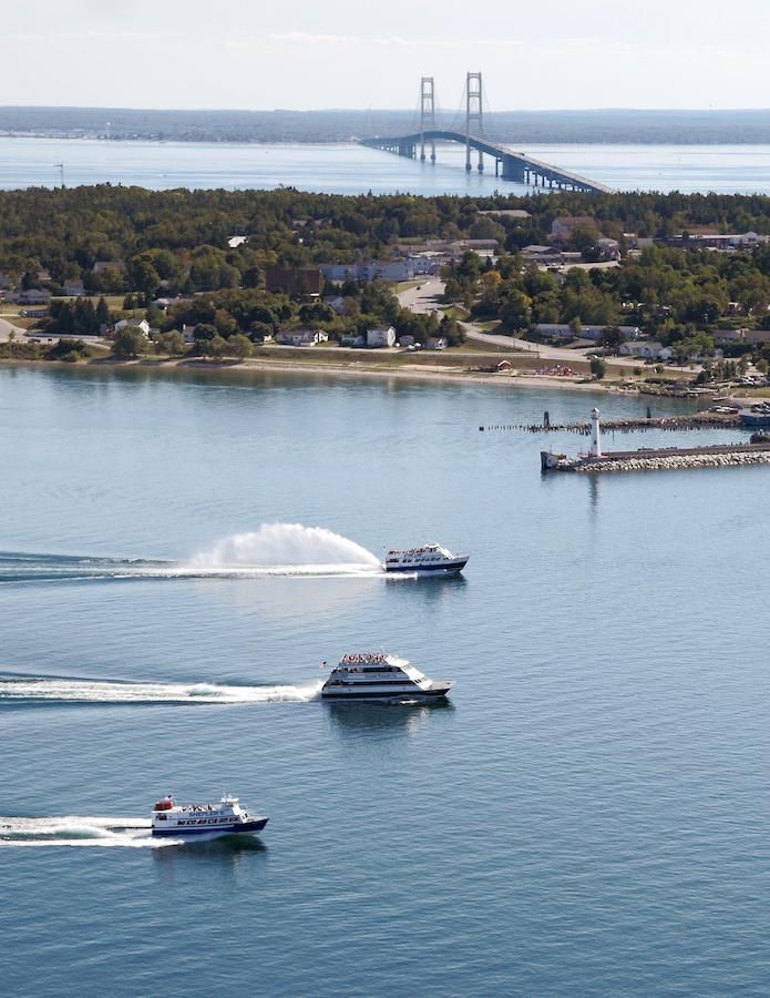 Three boats are in the water with a bridge in the background