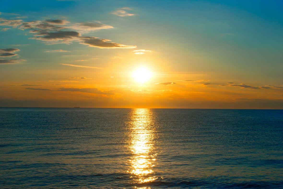 The sun is setting over the ocean and reflected in the water.