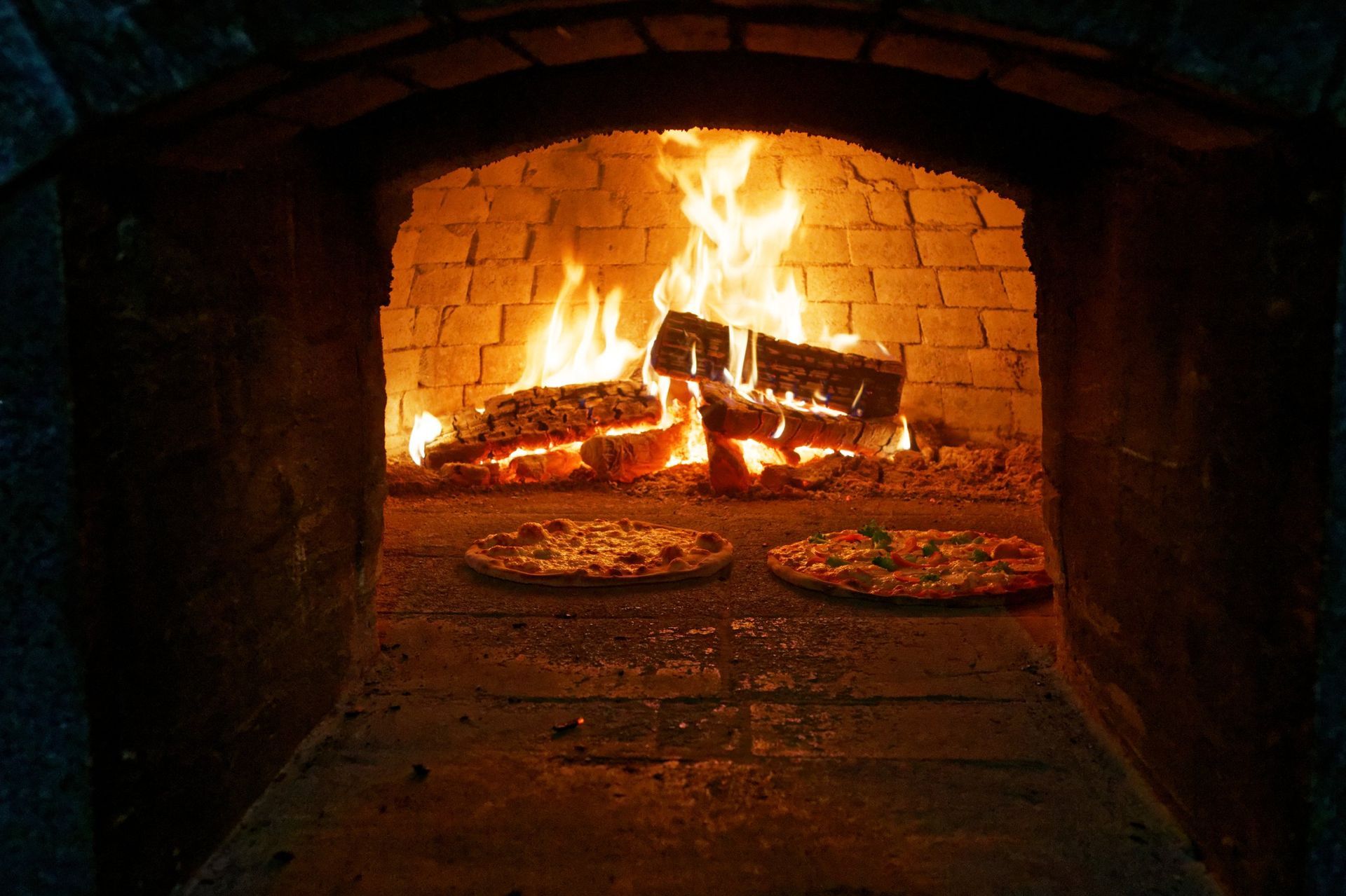 Two pizzas are being cooked in a fireplace