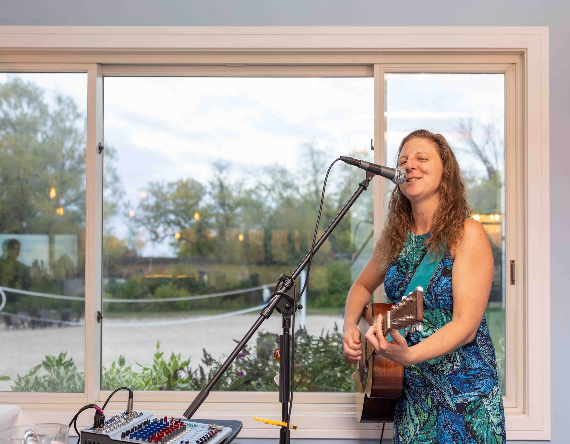 A woman is playing a guitar and singing into a microphone.