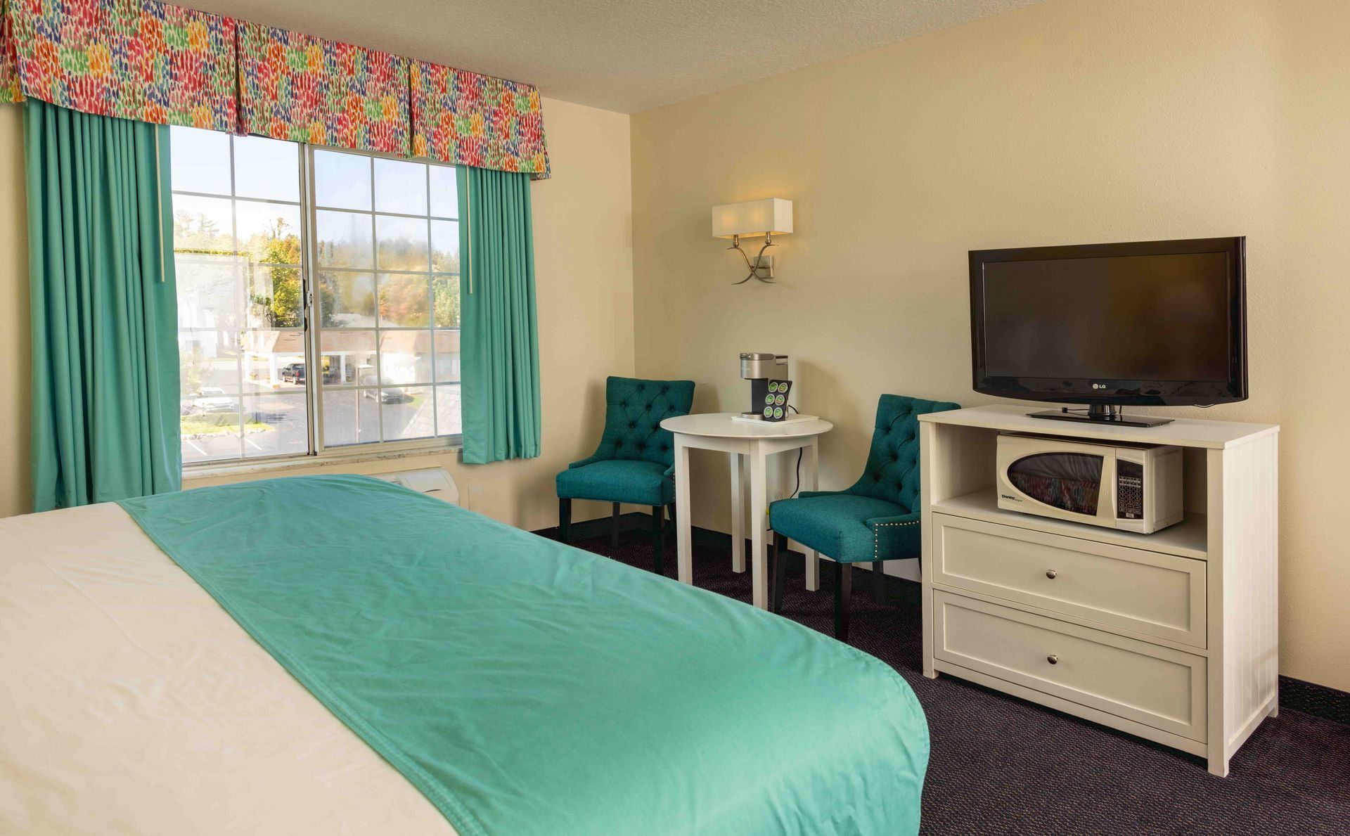 A hotel room with a king size bed , television , table and chairs.