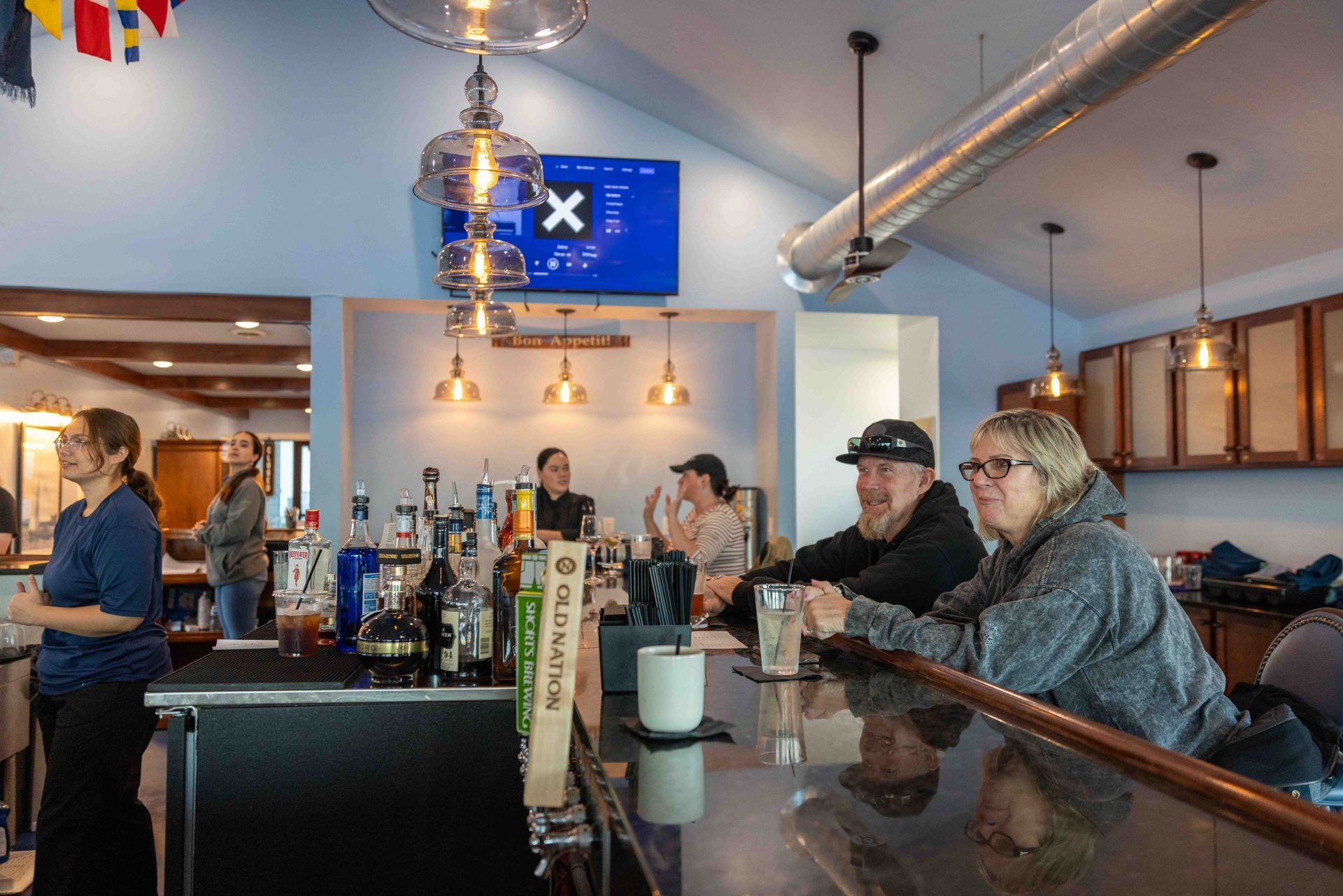 A group of people are sitting at a bar in a restaurant.