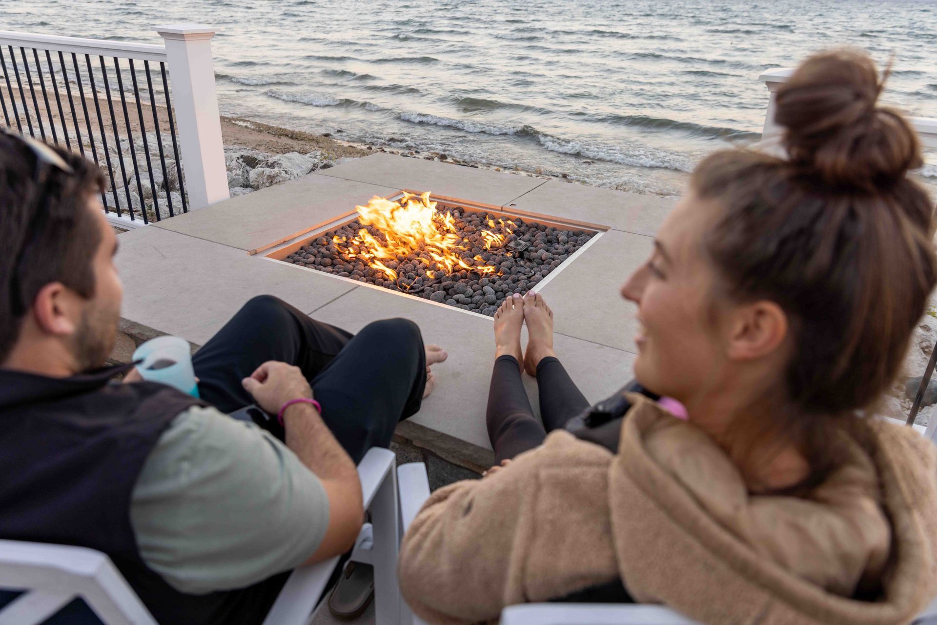 A man and a woman are sitting in chairs near a fire pit.