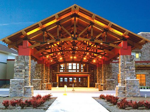 A large stone building with a wooden roof and a fountain in front of it.