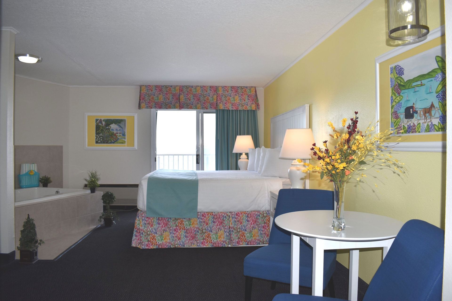 A hotel room with a king size bed a table and chairs