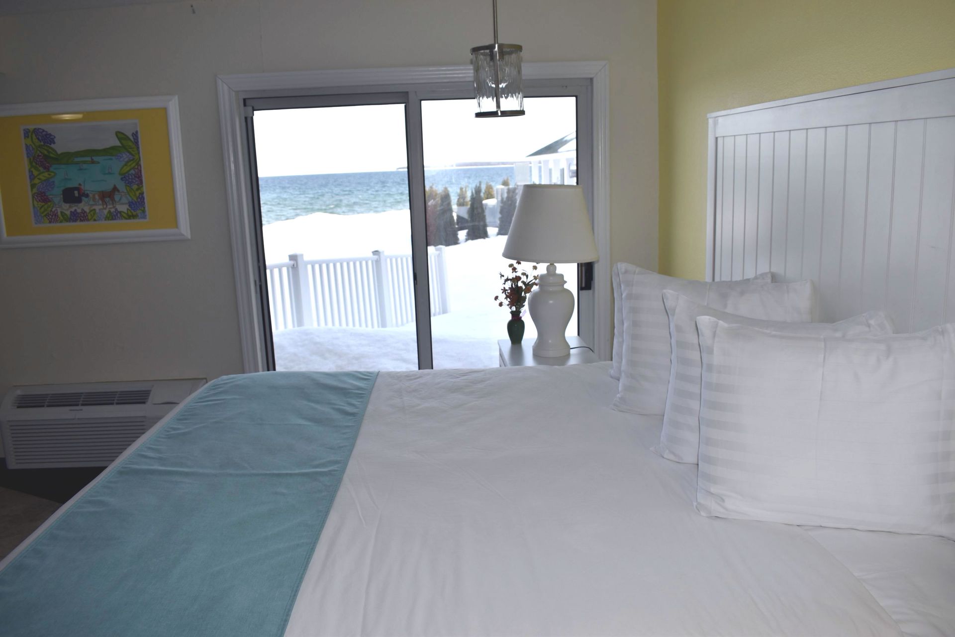 A hotel room with a king size bed and a sliding glass door leading to a balcony.