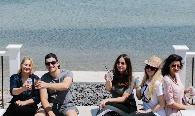 A group of people are sitting on a bench by the water.