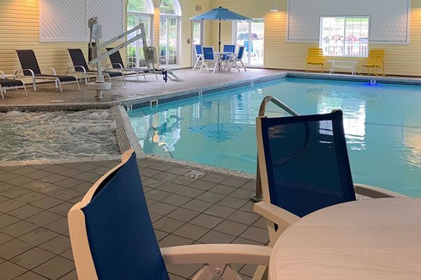 A swimming pool with chairs and a table in front of it