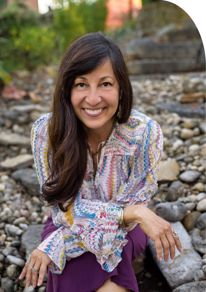 A woman is sitting on a pile of rocks and smiling.