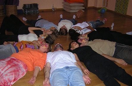 A group of people are laying on the floor in a circle.