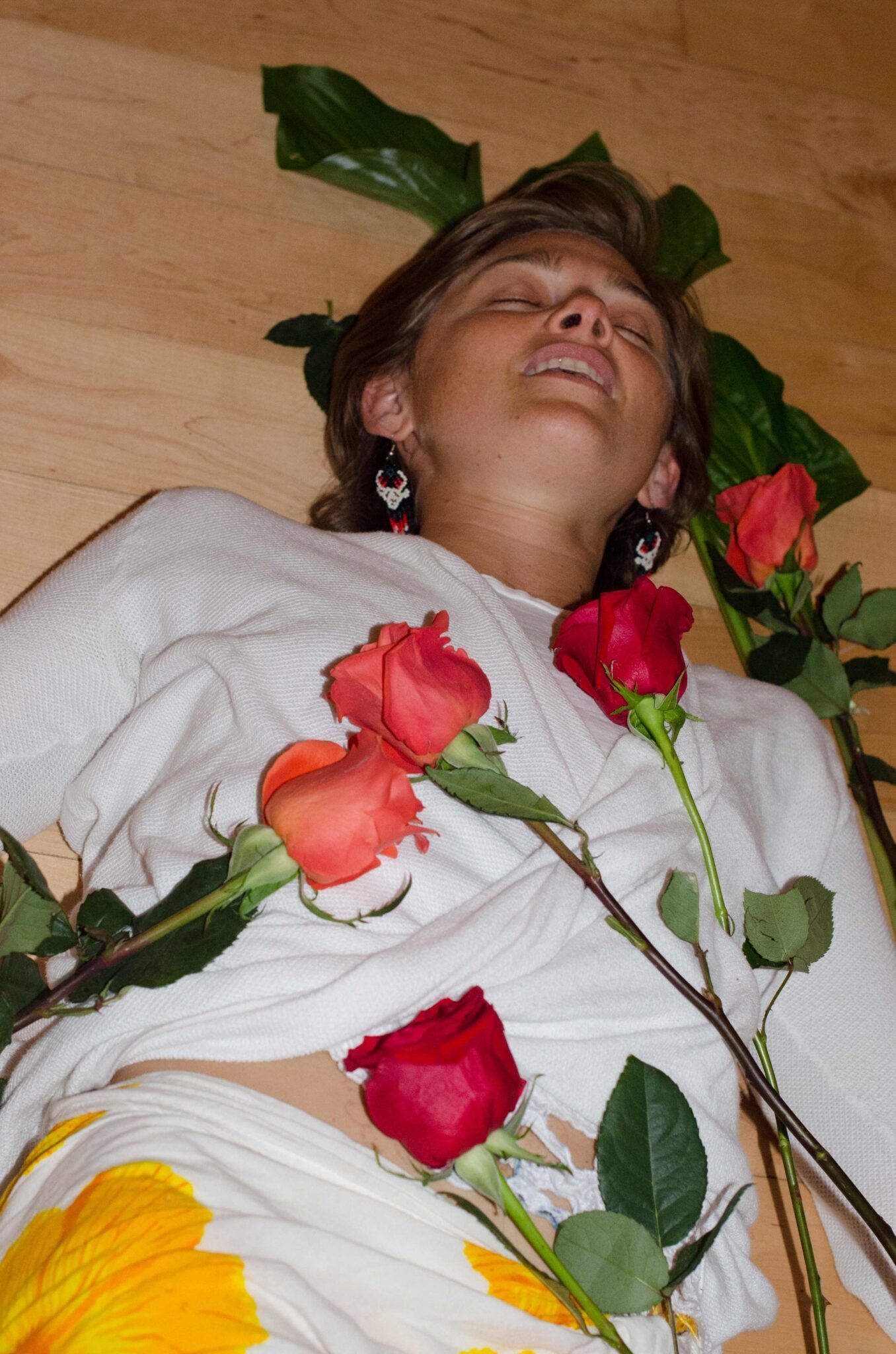 A woman laying on the floor with roses around her neck