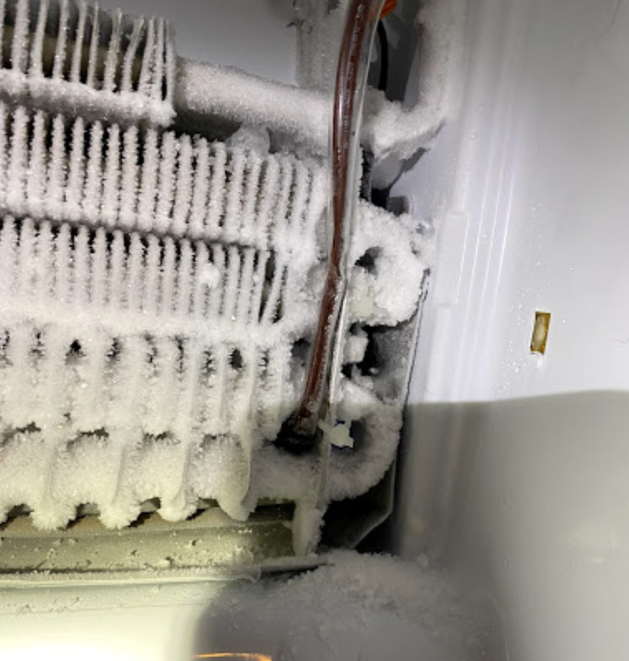 The inside of a refrigerator with a lot of ice on it.